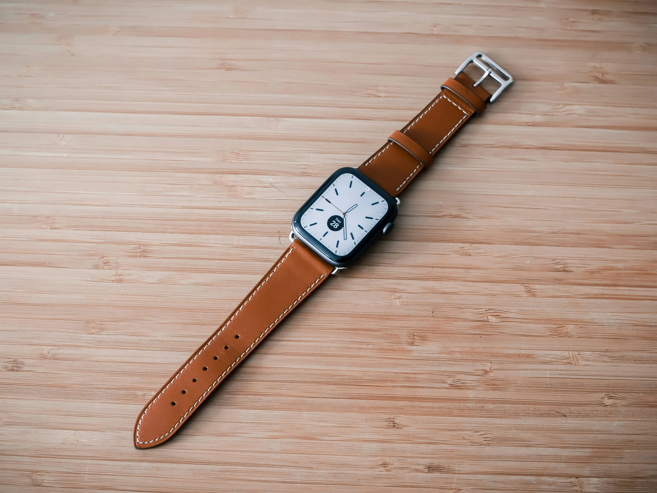 a brown apple watch strap sitting on a wooden table