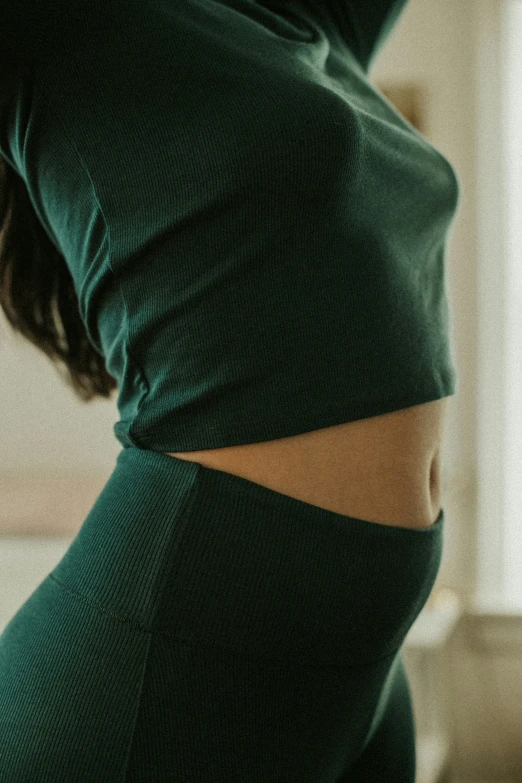 a woman standing in a room wearing green pants