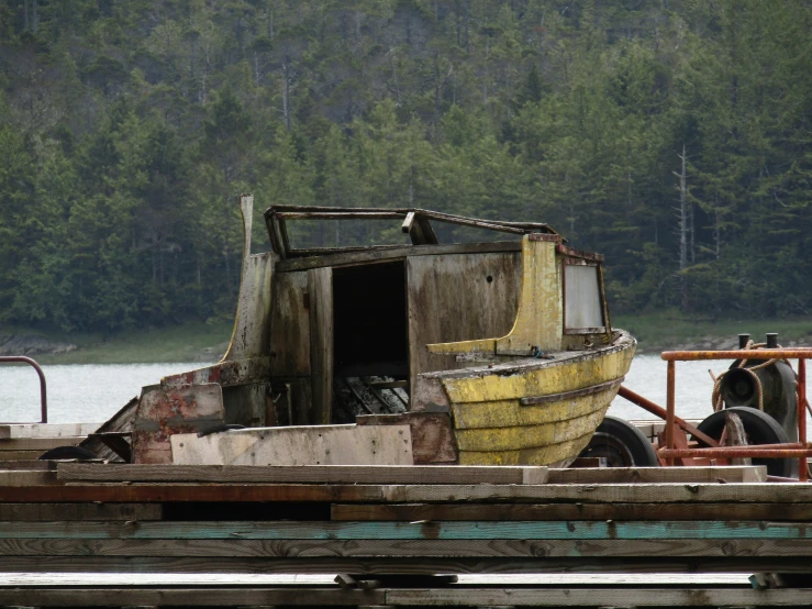 an abandoned wooden boat sits on a lake pier