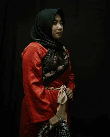 a woman in a red coat with a bag and a black background