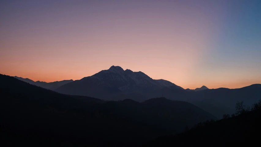 a mountain with a bright sun in the background