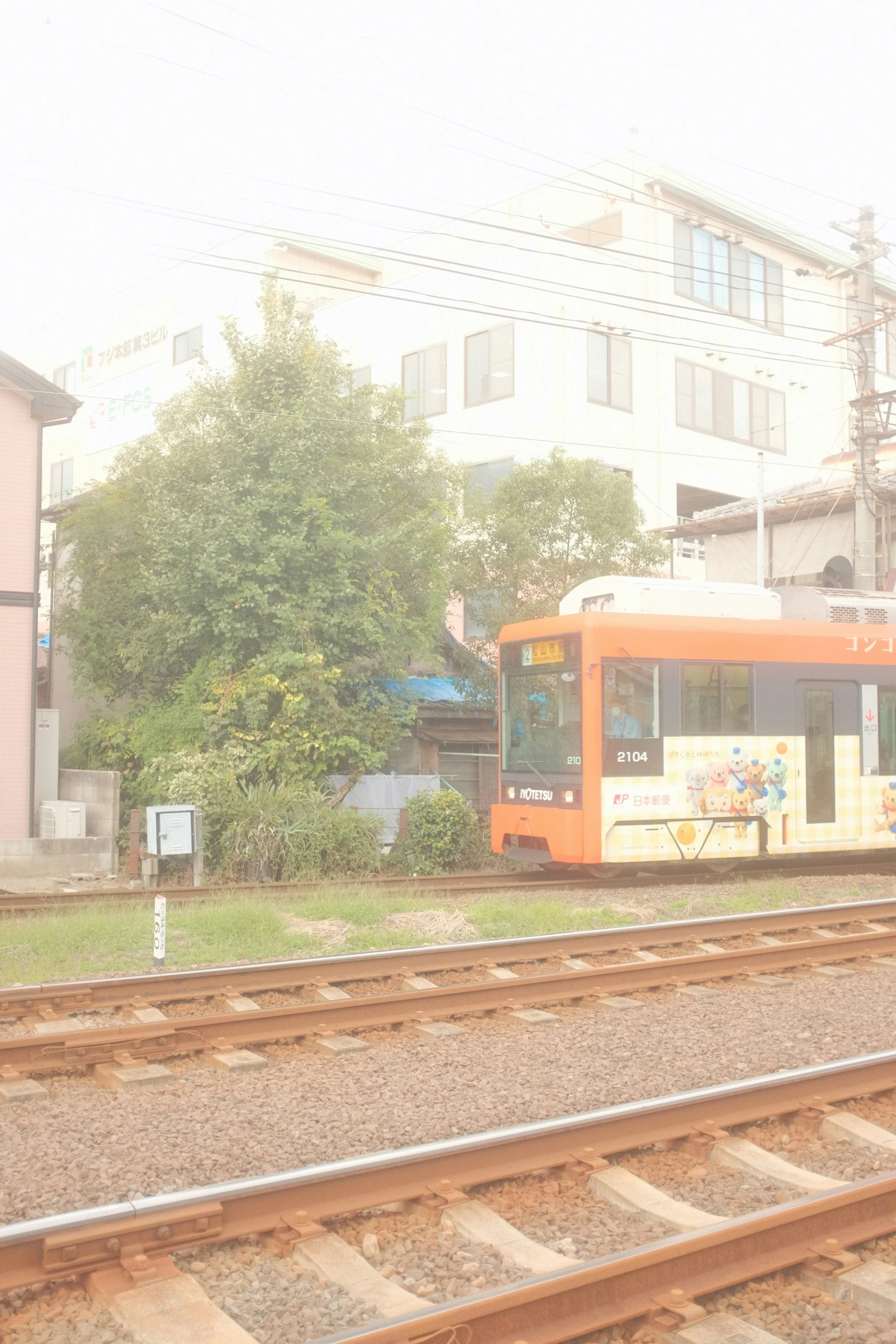 a orange colored train is on a track near some houses