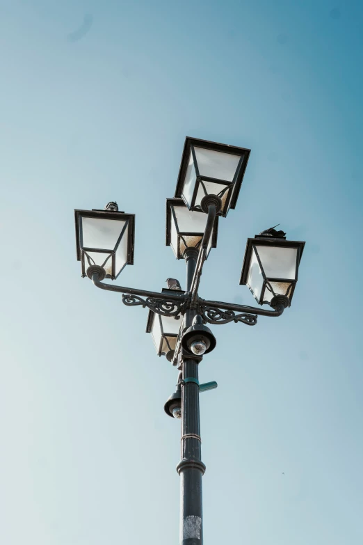 four street lights next to each other in front of the sky