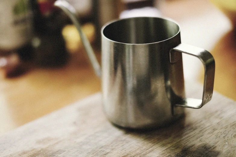 a metal cup sitting on top of a wooden table