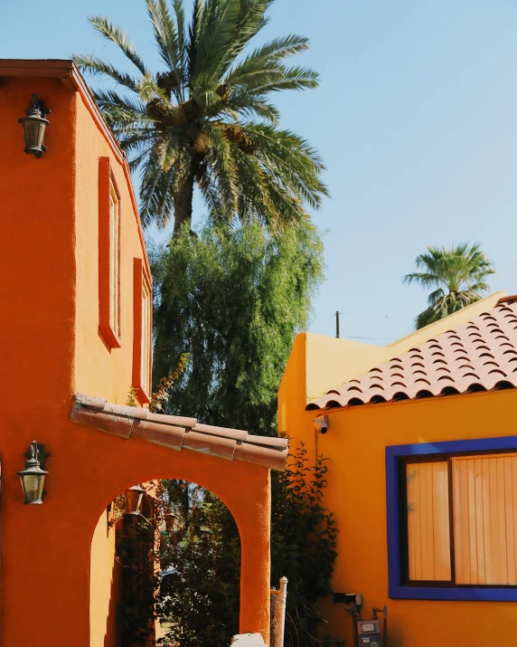 a red building with blue shutters near palm trees