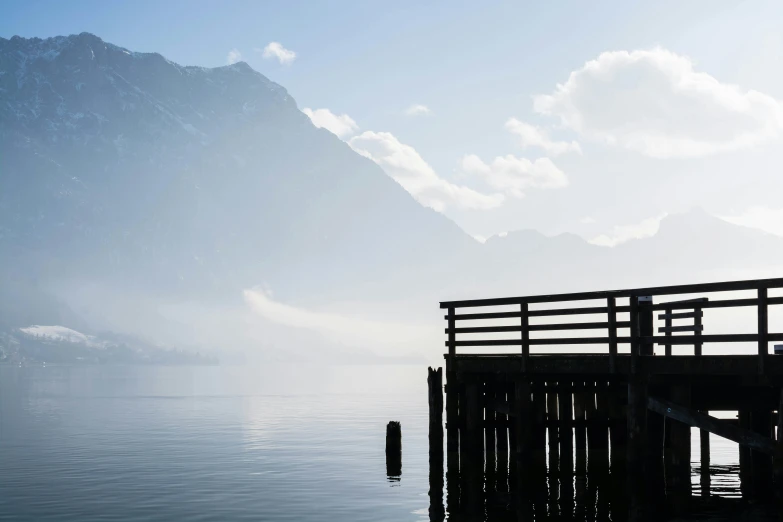 a wooden pier in the fog near mountains