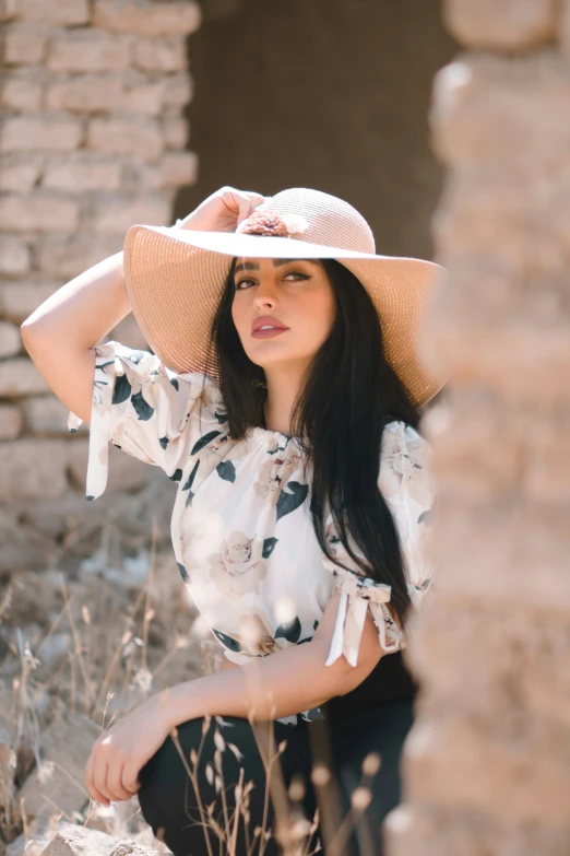 the woman wearing a hat is standing near a brick wall