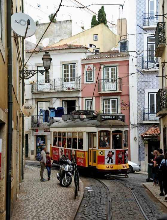 people are on a cobblestone street, walking by a trolley in the city