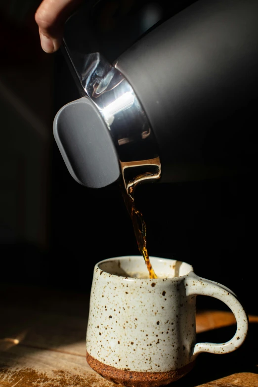 a person pouring coffee into a cup on a table