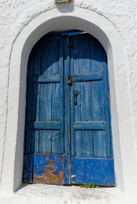 the blue door to a stone building has peeling paint on it