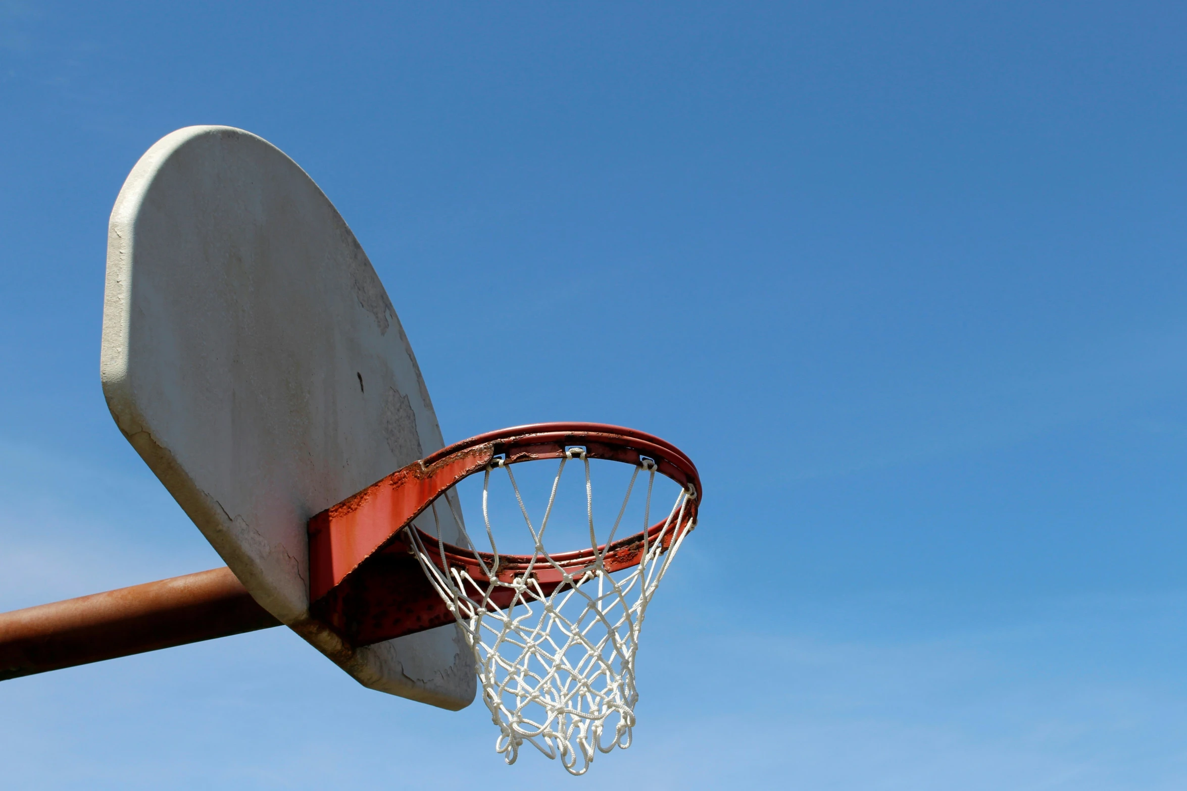 a basketball hoop and net against a bright blue sky