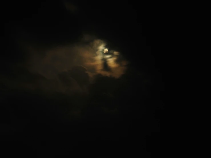 a dark moon is seen behind the clouds