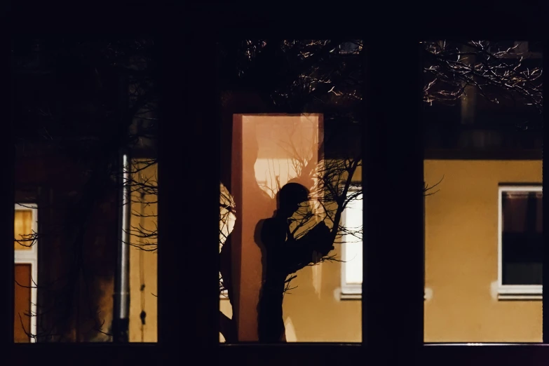 a person in a dark room with trees outside