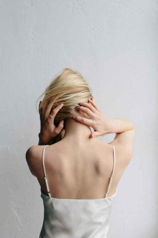 a blonde woman wearing a tank top with her hand on her shoulder