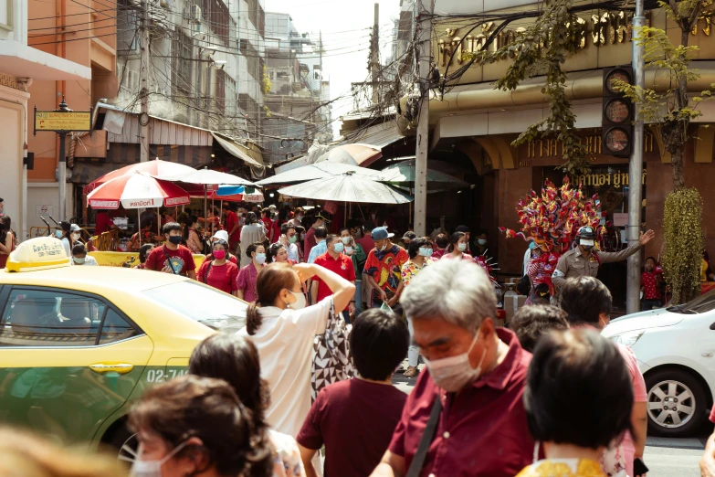 a crowded street filled with people standing and sitting under umbrellas