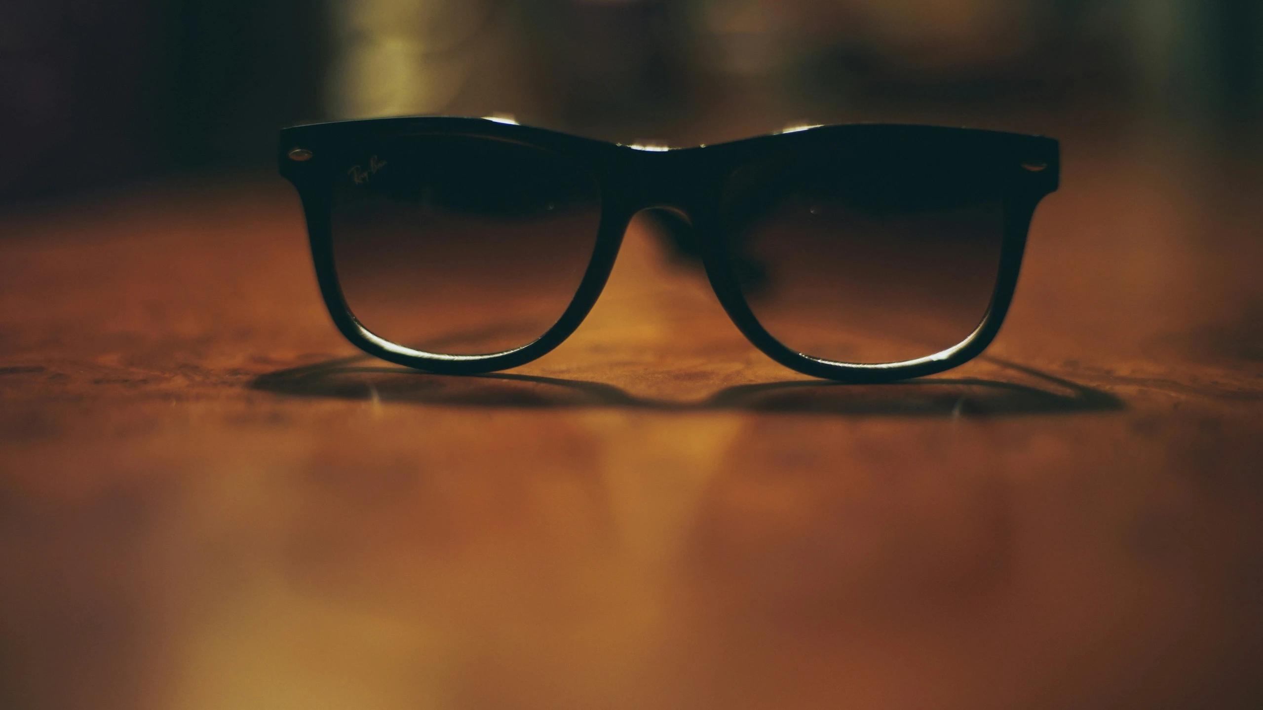 a pair of black sunglasses on a wooden table