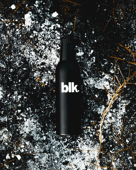 a black bottle with white label in the middle on cement