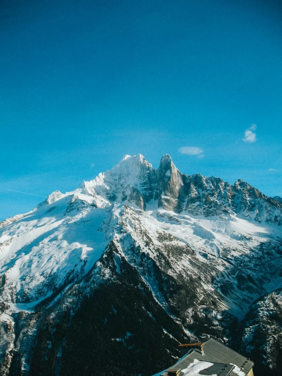 snow - covered mountains are behind a small building