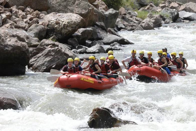 several people in red rafts in white water rapids