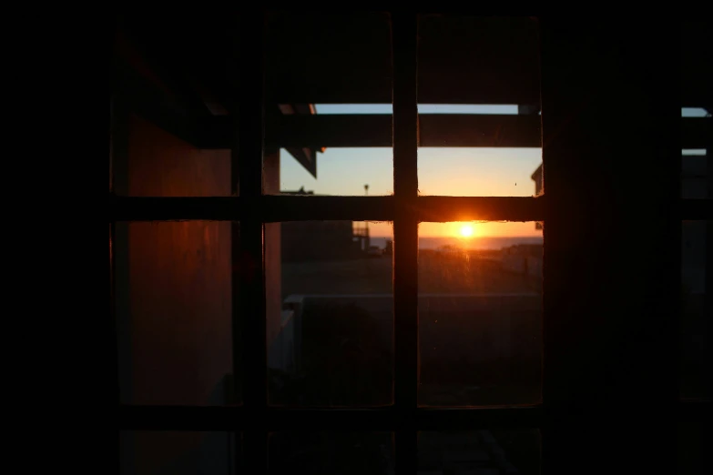 the sun setting in front of a window that has been partially obscured
