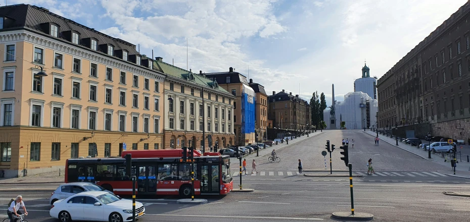 a bus and car going down a road surrounded by old buildings