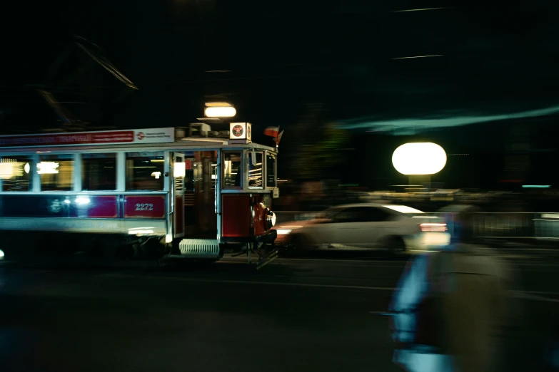 a tram car with headlights on driving down a street