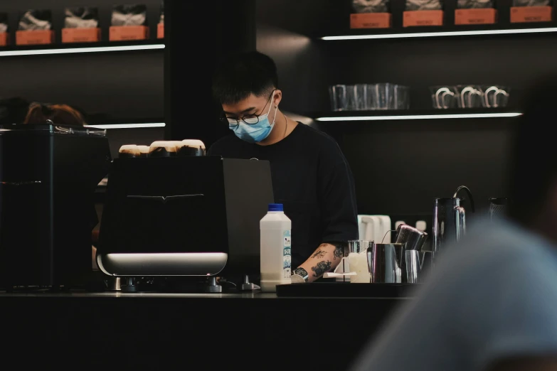 a man at a counter wearing a face mask and glasses