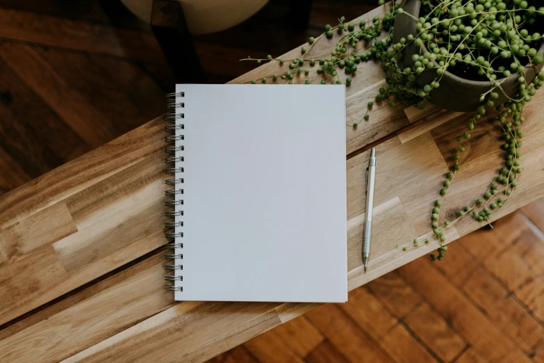 a notepad sitting next to a flower arrangement on a wood table