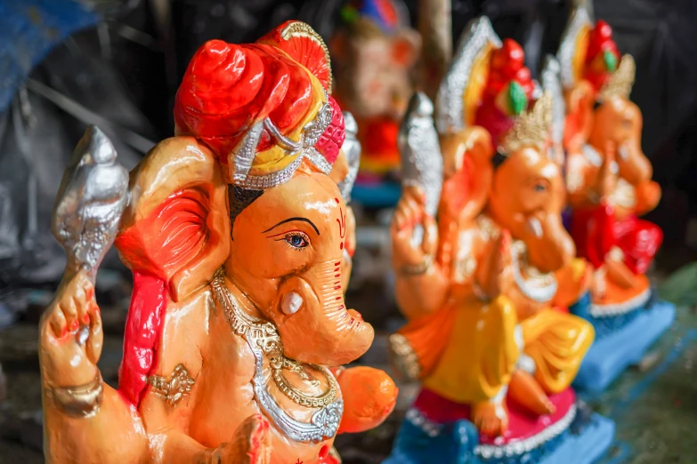 some decorative colored clay statues sitting in the shape of elephants