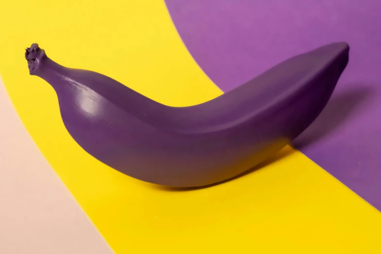 a purple banana sitting on a yellow and purple background