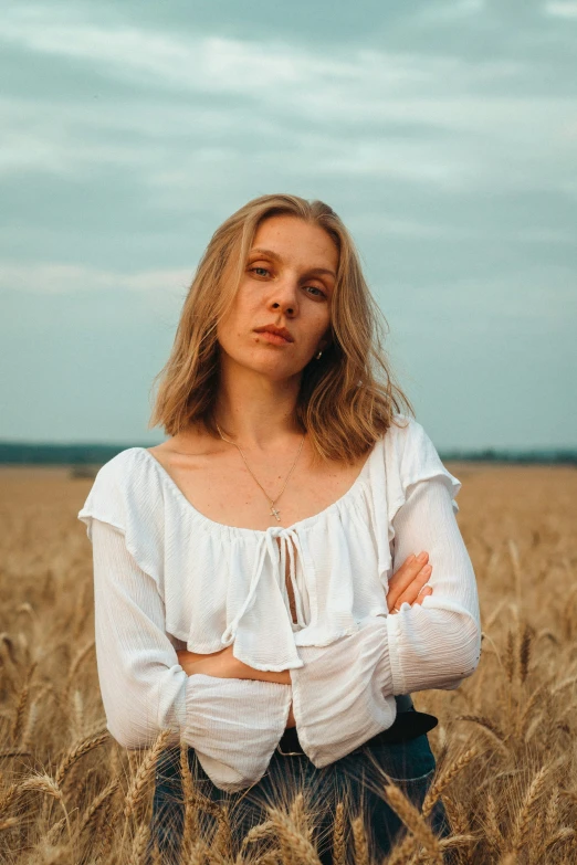 a girl with white top and brown pants stands in a field