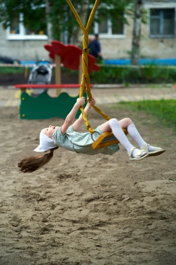 a young child swinging from a yellow monkey bar