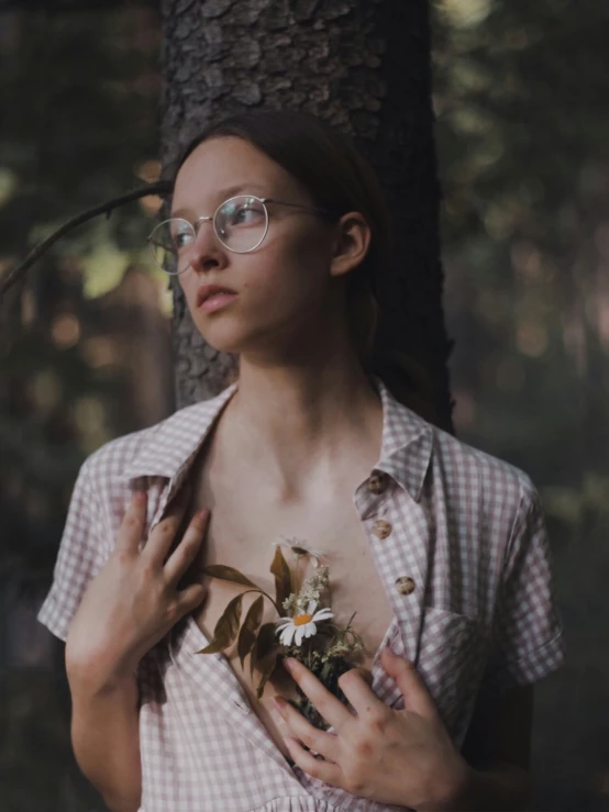 a woman wearing a gingham dress standing by a tree