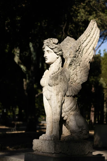 a sculpture of an angel sitting on a cement stand