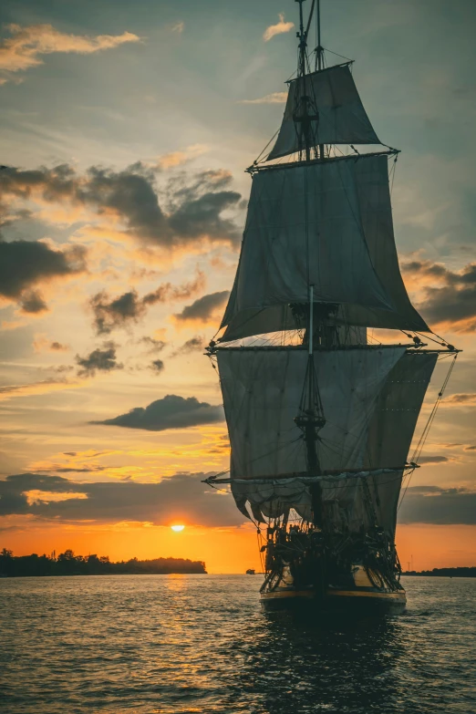 a large white sailboat sailing on a lake at sunset