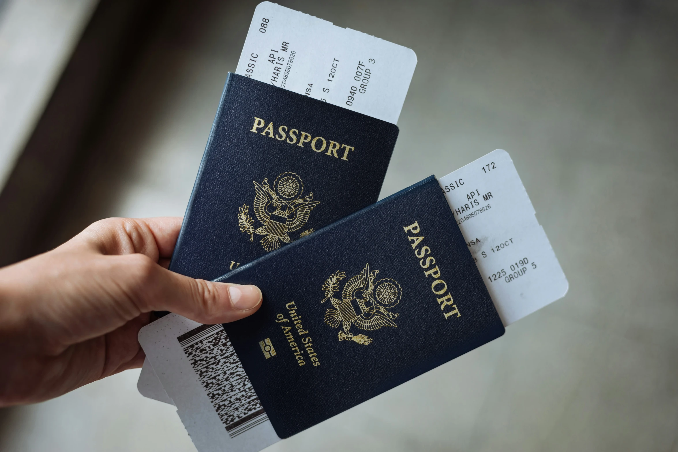 a person holding two passports in one hand and an passport in the other