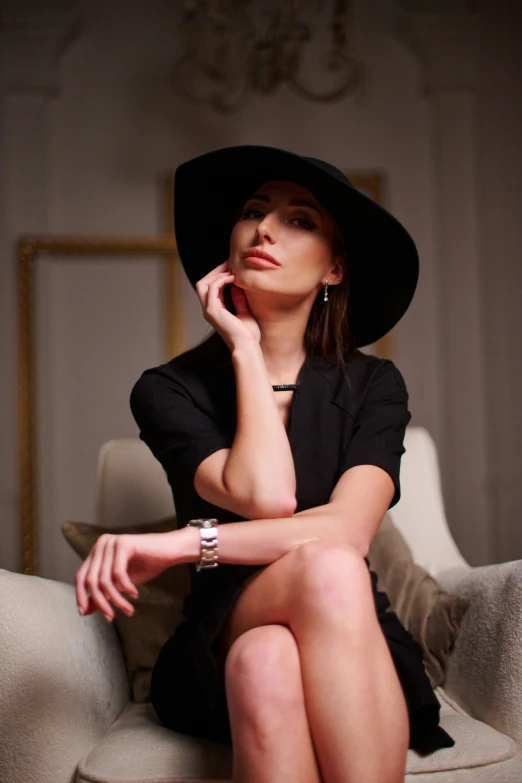 a woman wearing a black hat sitting on top of a couch