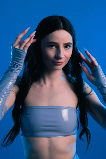 a woman poses in a blue dress with silver gloves