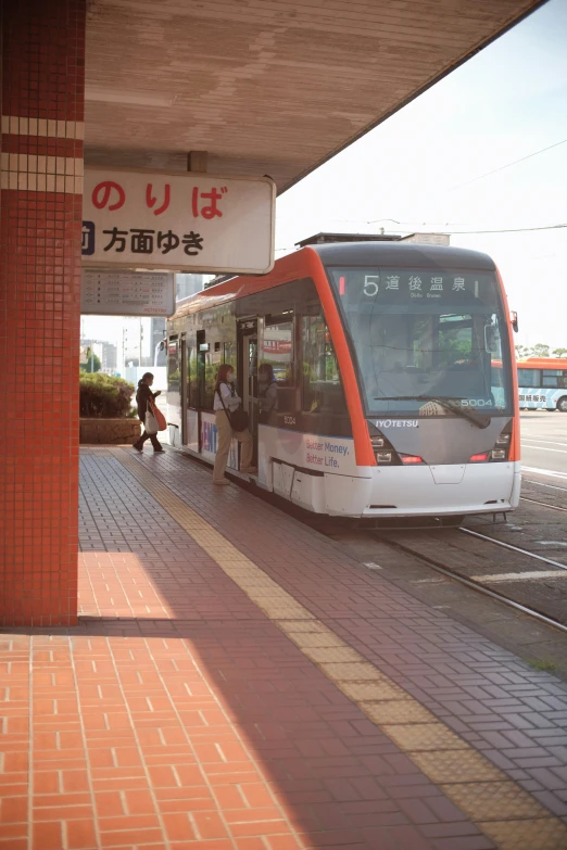 a long train driving past a red brick building