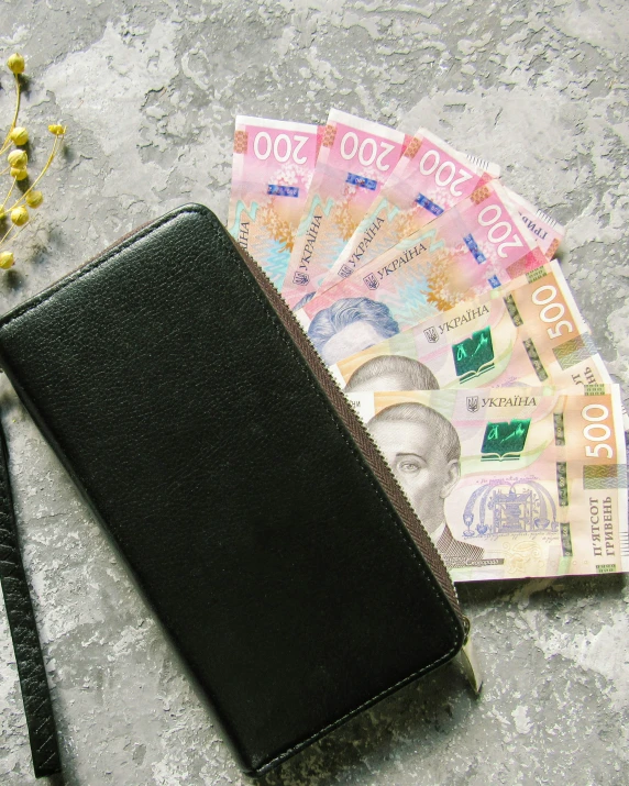 the wallet is next to three different foreign currency notes