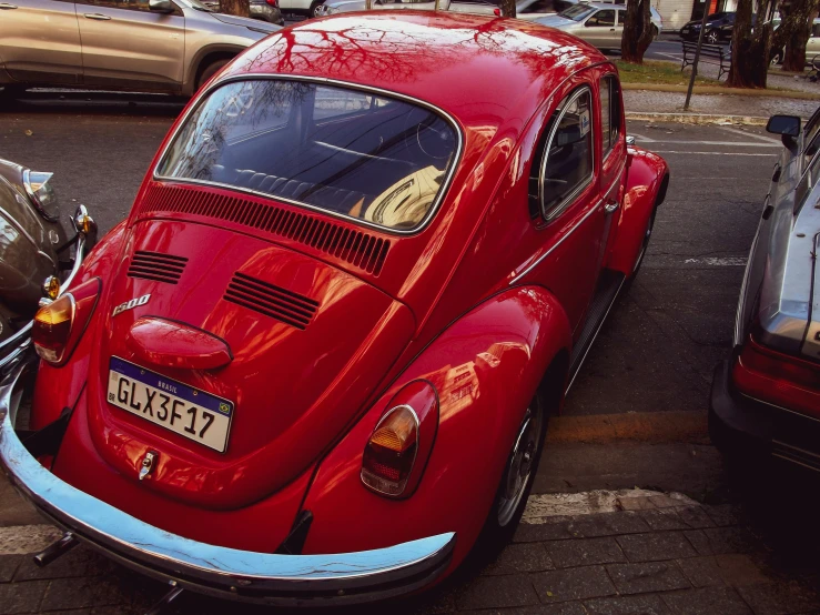 a red old car with a license plate parked next to another