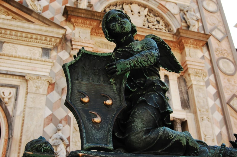 a statue of a kneeling man on a chair in front of a building