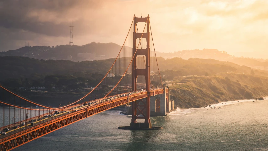 cars drive over the golden gate bridge during sunrise