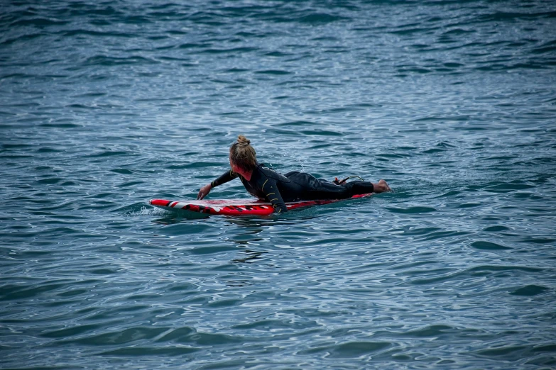 a woman laying on her surfboard in the ocean