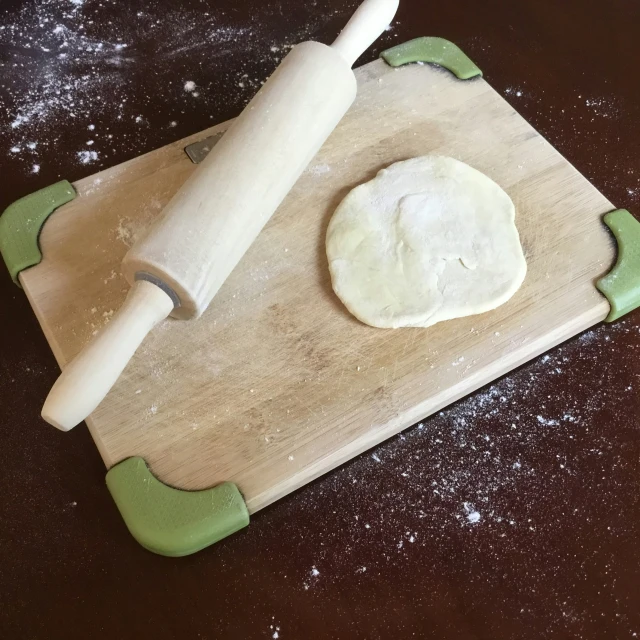 a small white dough being made on a wooden  board