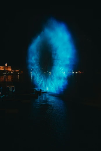 a big bright blue light up the night sky in the water
