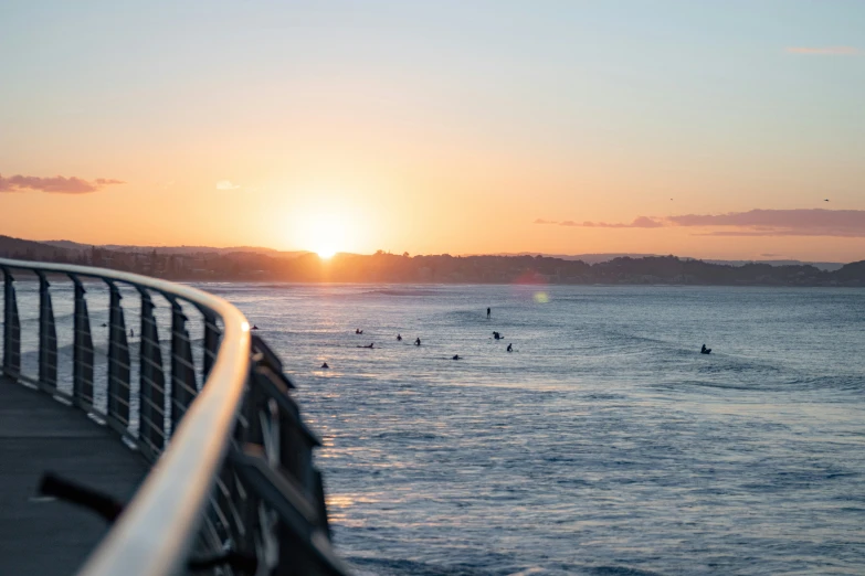 people are swimming in the ocean as the sun sets