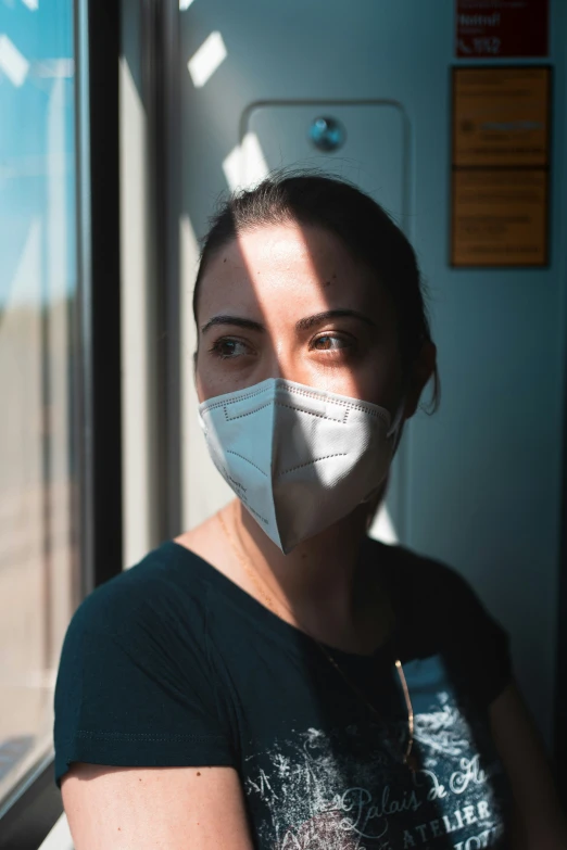 a woman wearing a mask looking out the window