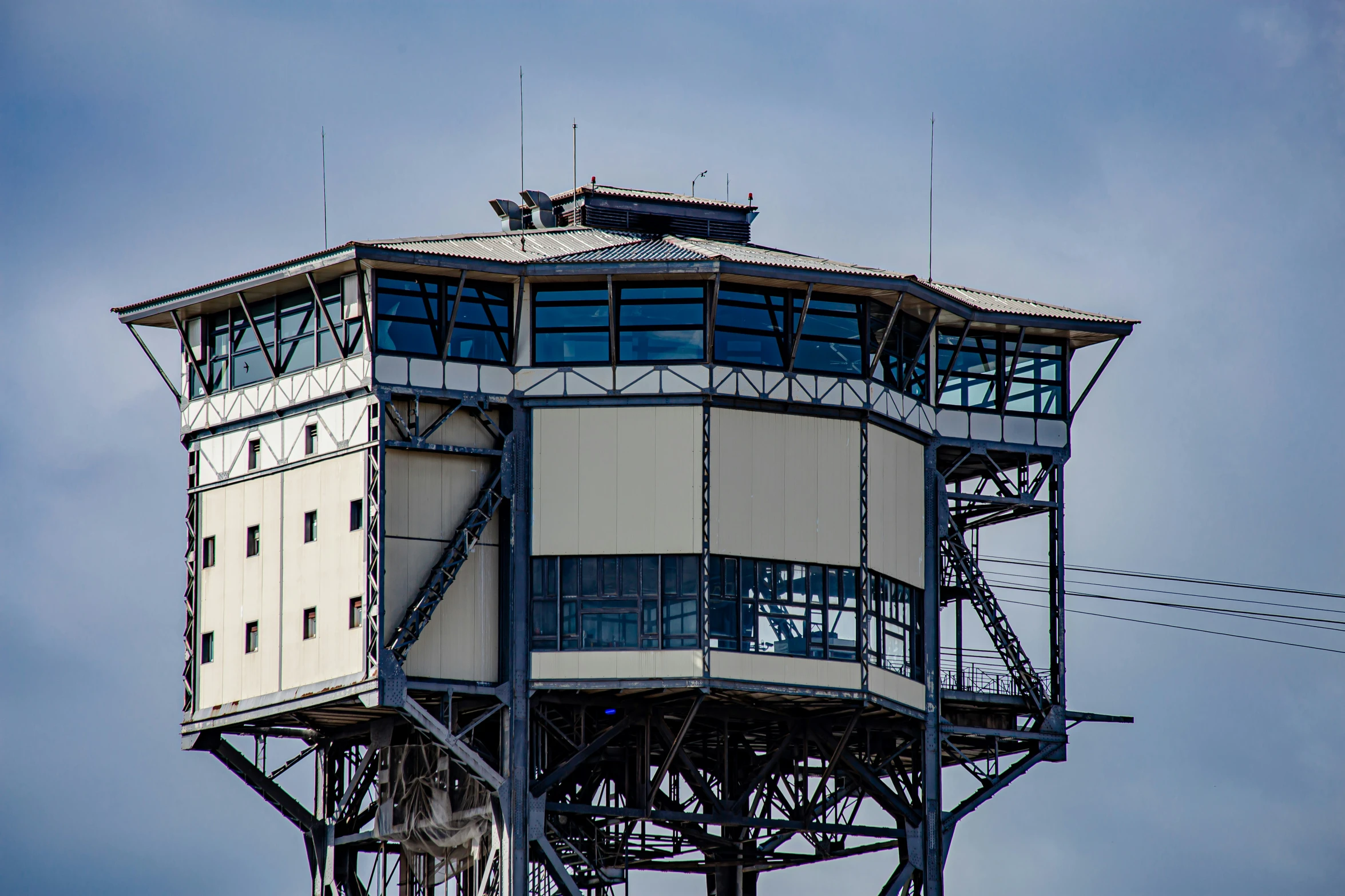 a tall white tower sitting in the sky next to telephone wires