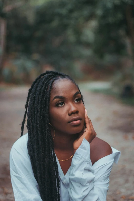 a woman sitting on the ground with her hair tied in a side ponytail